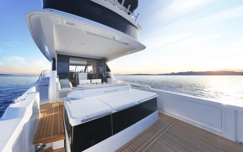 Slide: The Image of 2026 Maritimo M600 yacht on serene water at sunset, showcasing sleek design and spacious deck. - 6