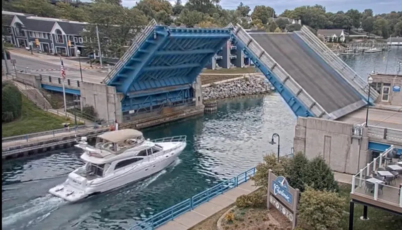 Slide: The Image of A 2001 Cruisers 5000 Sedan yacht passing under an open drawbridge in a scenic canal. - 1