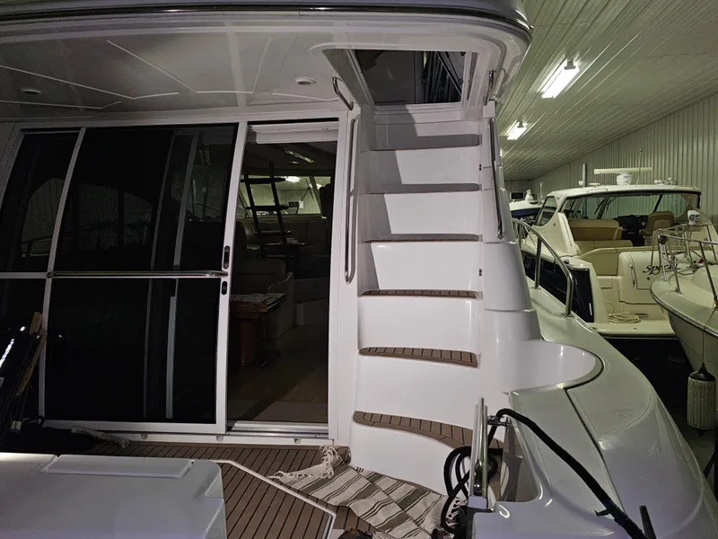 Slide: The Image of 2001 Cruisers 5000 Sedan yacht interior with stairs and sliding door in a well-lit showroom. - 10