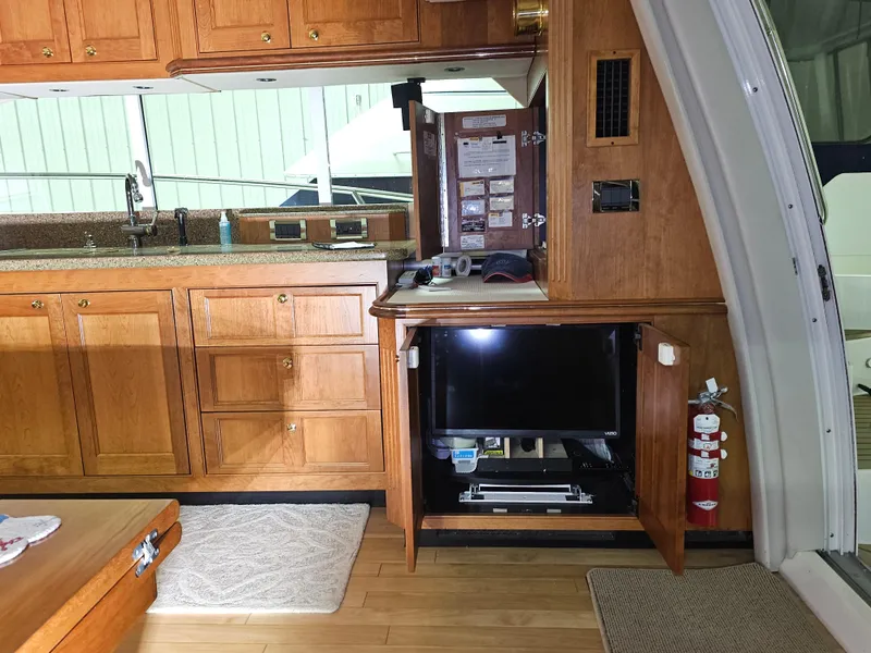 Slide: The Image of 2001 Cruisers 5000 Sedan interior with wooden cabinetry, TV, and kitchen area. - 18