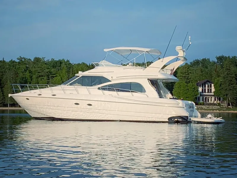 Slide: The Image of 2001 Cruisers 5000 Sedan yacht on calm water with forested shoreline. - 2