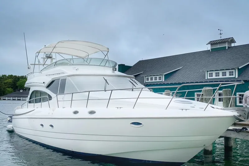 Slide: The Image of 2001 Cruisers 5000 Sedan yacht docked near a waterfront building. - 3