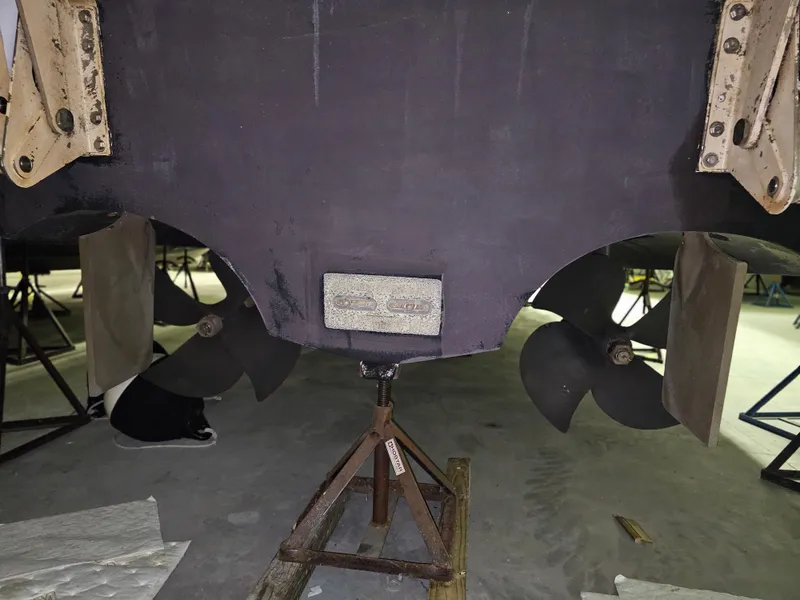 Slide: The Image of 2001 Cruisers 5000 Sedan boat propellers and hull on stands in a workshop. - 35