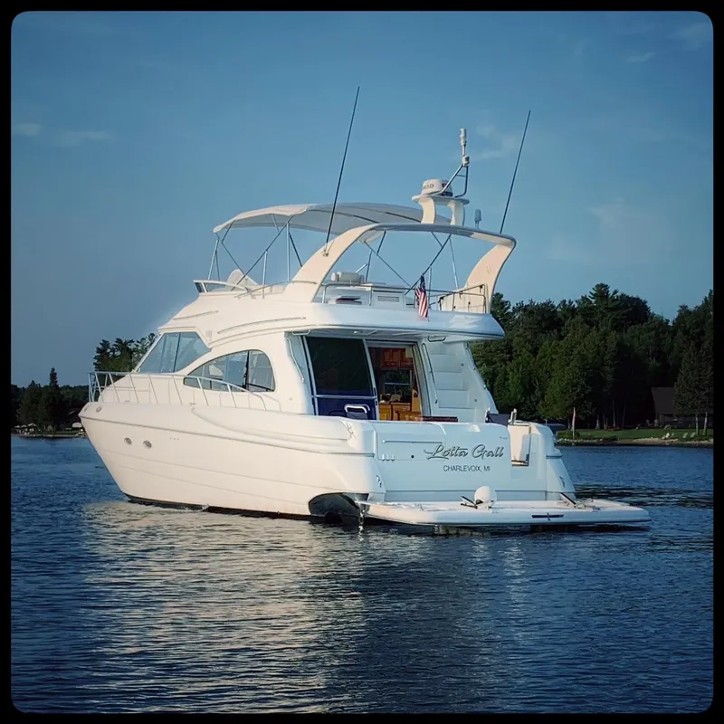 Slide: The Image of 2001 Cruisers 5000 Sedan yacht on calm water with forested shoreline. - 4