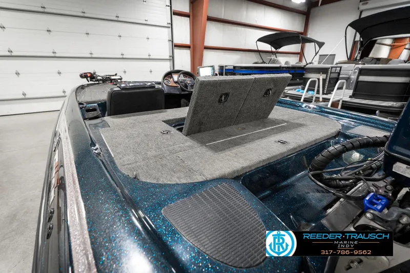 Slide: The Image of 1999 Triton TR-20 boat interior in a garage, featuring carpeted deck and storage compartments. - 28