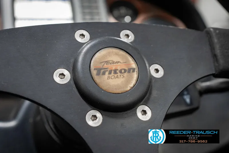 Slide: The Image of Steering wheel of a 1999 Triton TR-20 boat with logo and branding. - 32