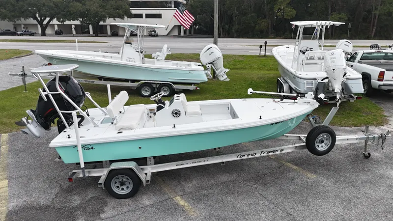 Slide: The Image of 2023 Vtech 18 boat on trailer, parked with other boats, American flag in background. - 2