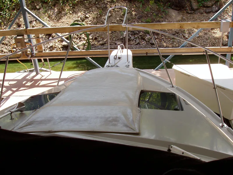 Slide: The Image of 1990 Carver Mariner 32 boat docked, featuring a covered deck and railing. - 10
