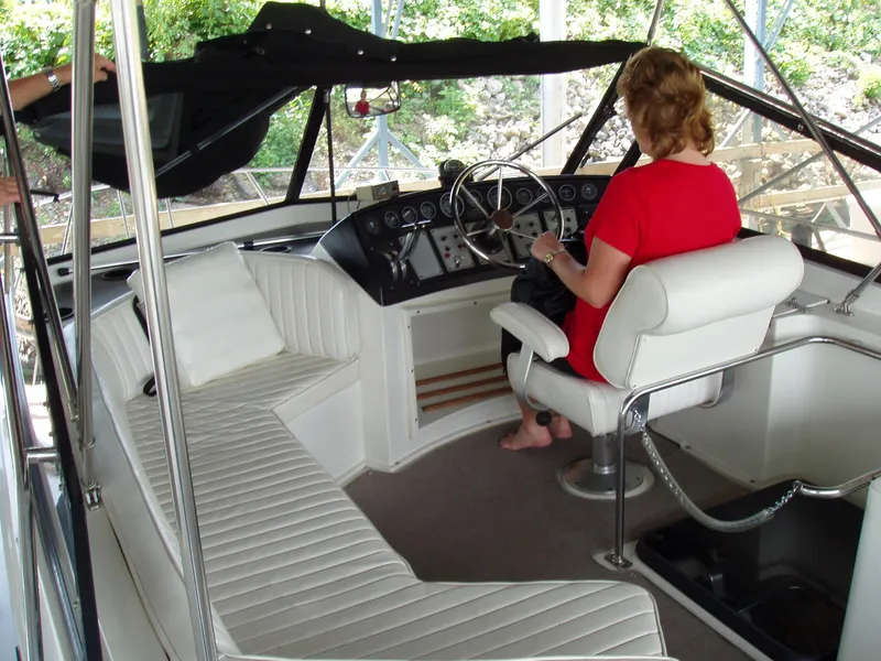 Slide: The Image of Woman steering a 1990 Carver Mariner 32 yacht, featuring white seating and a sleek dashboard. - 11
