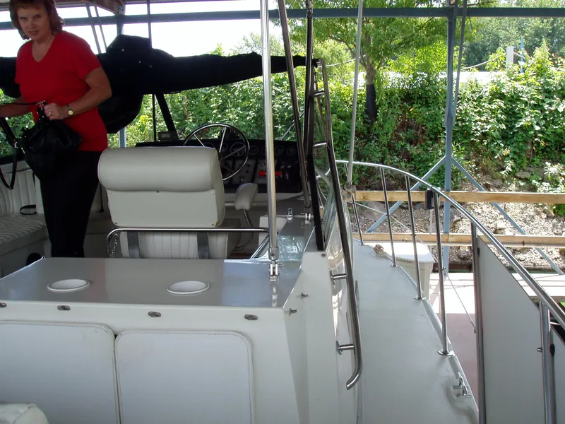 Slide: The Image of 1990 Carver Mariner 32 boat interior with seating and steering area, person in red shirt. - 12