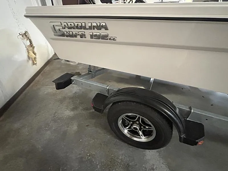 Slide: The Image of 2024 Carolina Skiff 192 JLS boat on trailer, showcasing side view and wheel detail. - 9