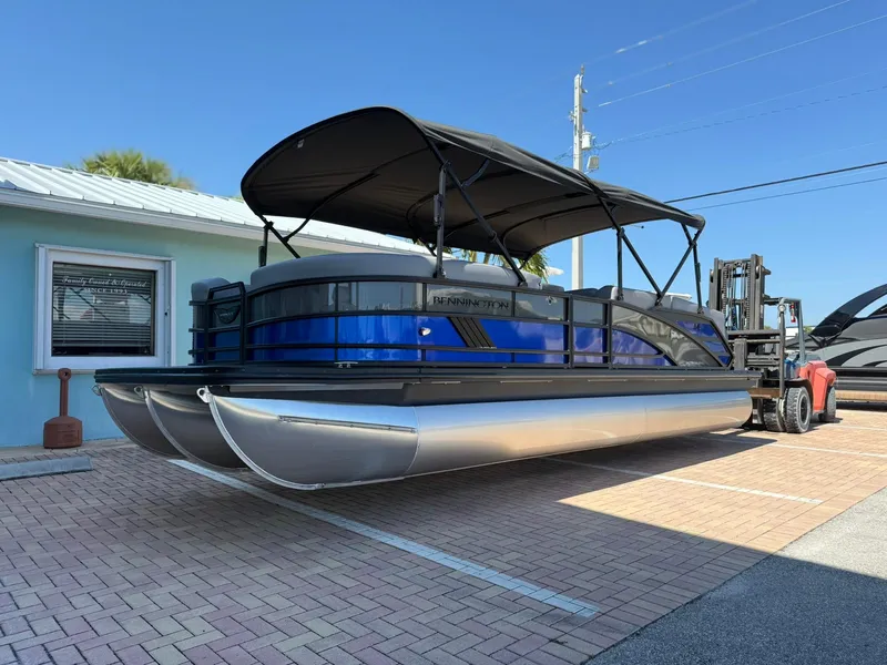 The Image of 2025 Bennington 24 MFB pontoon boat with blue accents, parked outdoors on a sunny day. - 1