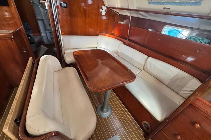 Slide: The Image of Interior of 1994 Beneteau 40 sailboat with wooden dining area and white cushioned seating. - 91