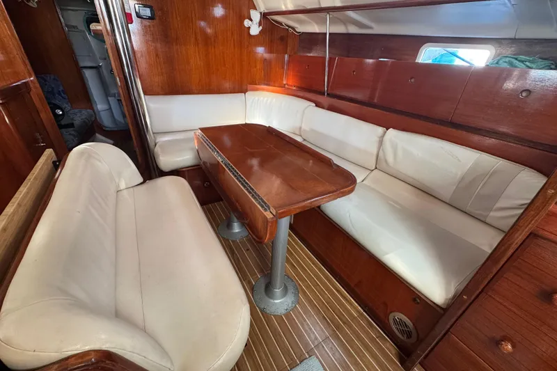 Slide: The Image of Interior of 1994 Beneteau 40 sailboat with wooden table and white seating. - 92