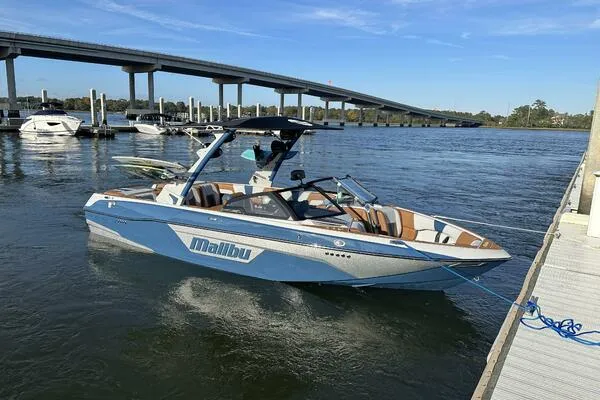 Slide: The Image of 2023 Malibu Wakesetter 23 LSV boat docked on a sunny day by a bridge. - 7
