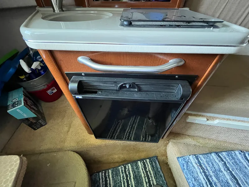 Slide: The Image of Interior of a 2014 Sea Ray 240 Sundancer with a compact kitchenette and mini fridge. - 14