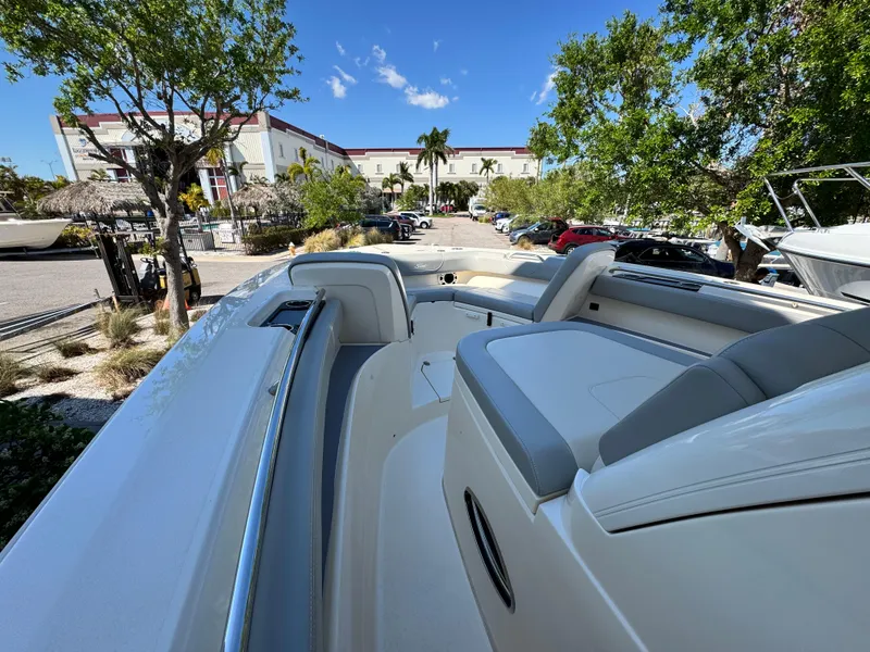 Slide: The Image of 2023 Scout 305 LXF boat interior with seating, parked outdoors under clear blue sky. - 13