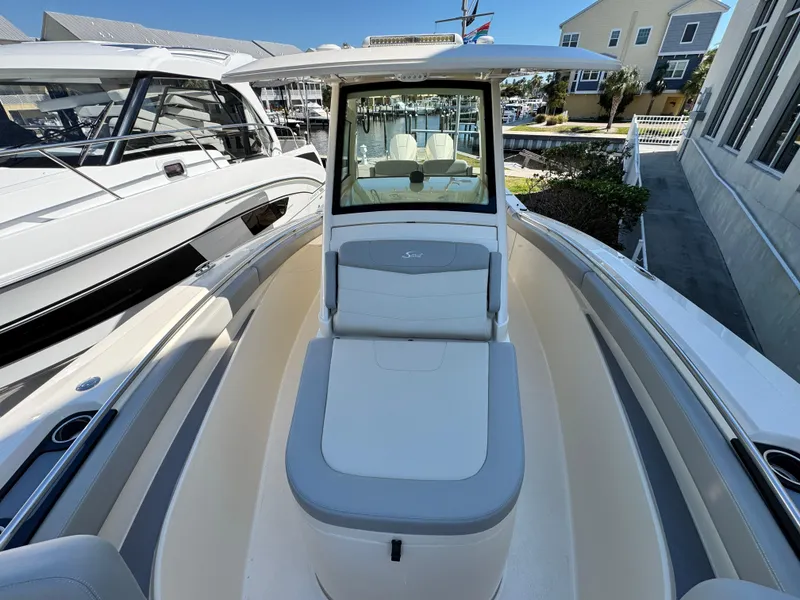 Slide: The Image of 2023 Scout 305 LXF boat with sleek design, docked near other vessels. - 14