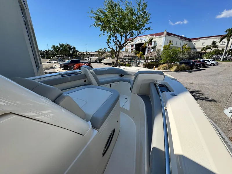 Slide: The Image of 2023 Scout 305 LXF boat with sleek seating, parked outdoors under a clear blue sky. - 18