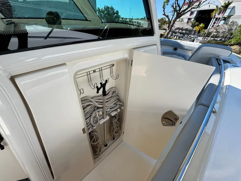Slide: The Image of 2023 Scout 305 LXF boat storage compartment with neatly organized ropes and hooks. - 20