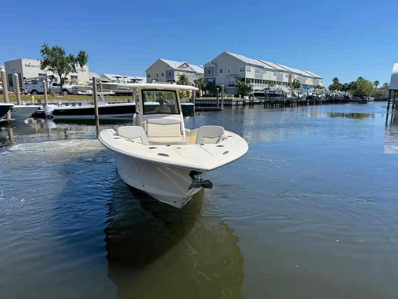 Slide: The Image of 2023 Scout 305 LXF boat on calm water near docks and waterfront homes. - 3