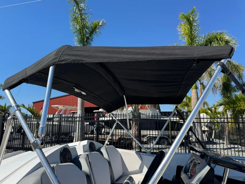 Slide: The Image of 2022 Scarab 165 ID boat with black canopy, parked near palm trees. - 30