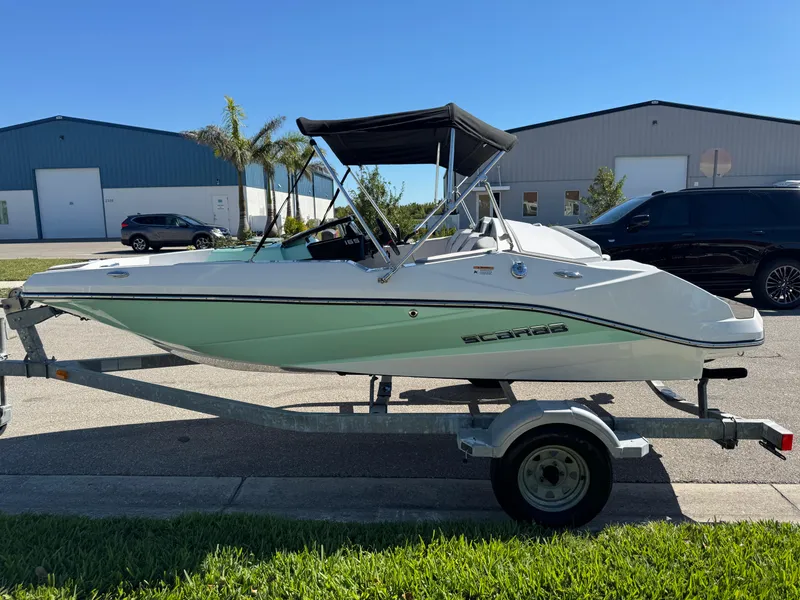 Slide: The Image of 2022 Scarab 165 ID boat on trailer, parked outdoors near industrial buildings. - 7
