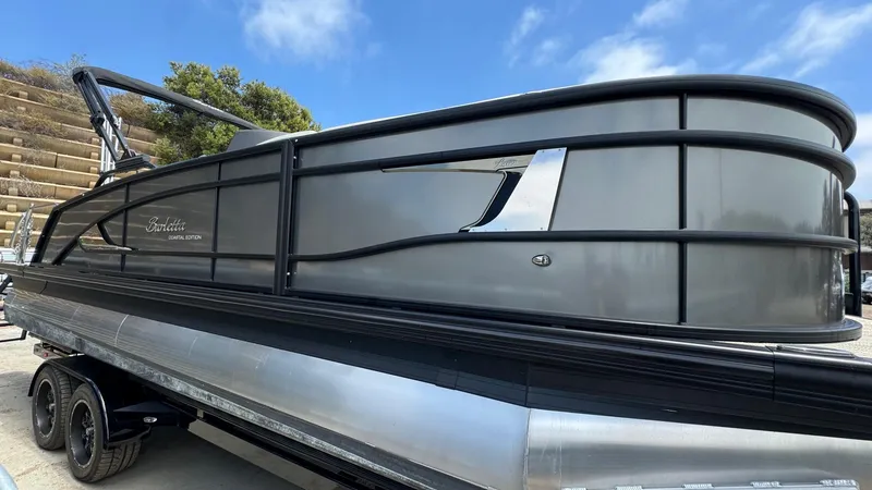 Slide: The Image of 2023 Barletta Lusso 23UC pontoon boat on trailer, sleek design under blue sky. - 13