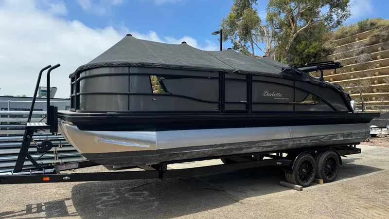 Slide: The Image of 2023 Barletta Lusso 23UC pontoon boat on trailer, covered and parked outdoors. - 2