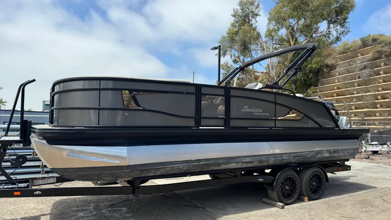 Slide: The Image of 2023 Barletta Lusso 23UC pontoon boat on trailer, sleek design, parked outdoors. - 4