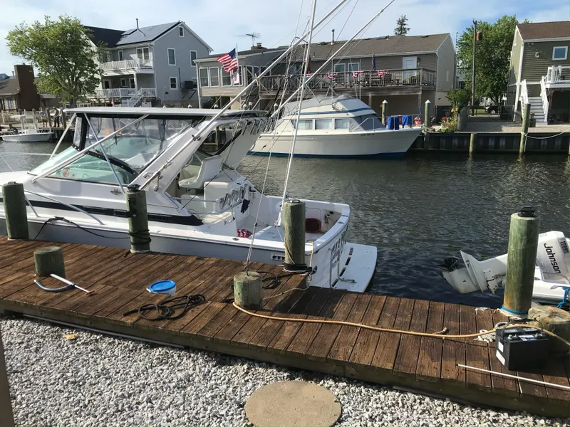 Slide: The Image of Bertram 30 Moppie 1995 docked at a marina with waterfront homes in the background. - 2