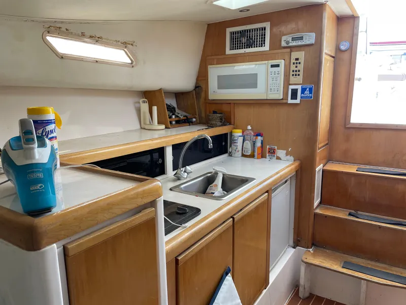 Slide: The Image of 1995 Bertram 30 Moppie yacht interior kitchen with sink, microwave, and wooden cabinetry. - 6