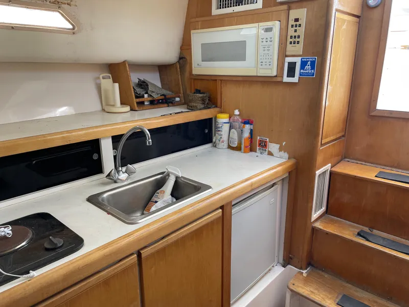 Slide: The Image of 1995 Bertram 30 Moppie boat kitchen with sink, microwave, and wooden cabinetry. - 7