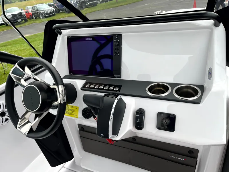 Slide: The Image of 2024 Axopar 22 boat dashboard with steering wheel, control panel, and cup holders. - 17