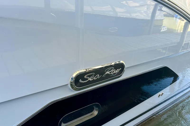 Slide: The Image of 2025 Sea Ray Sundancer 370 boat with logo detail, docked on calm water. - 50