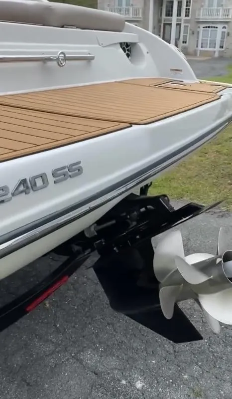 Slide: The Image of 2023 Crownline 240 SS boat with teak deck and propeller, parked outdoors. - 12