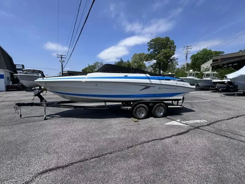 Slide: The Image of 2023 Crownline 240 SS boat on trailer in parking lot under clear sky. - 2