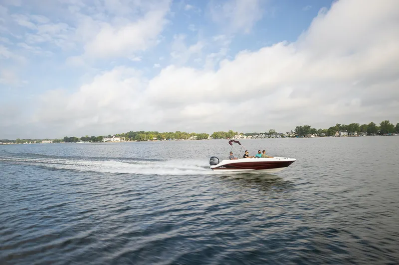 Slide: The Image of 2025 Hurricane SunDeck Sport 185 OB speeding on a lake under a cloudy sky. - 18