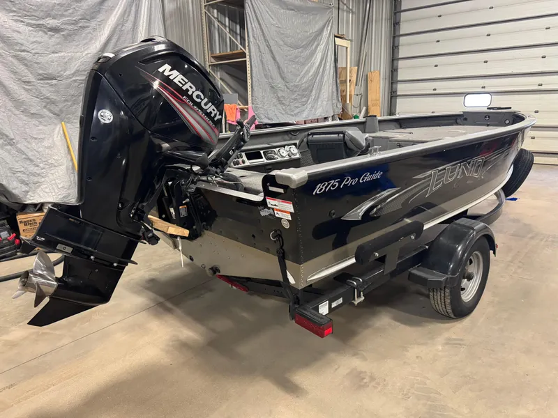 Slide: The Image of 2016 Lund 1875 Pro Guide boat with Mercury outboard motor in a garage. - 2
