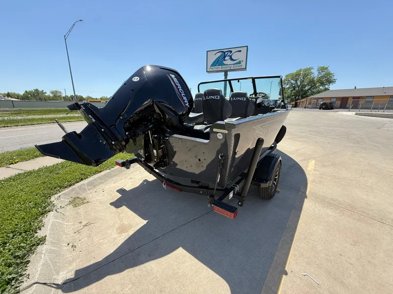 Slide: The Image of 2025 Lund 1650 Rebel XL Sport boat with outboard motor on trailer, parked outdoors. - 2