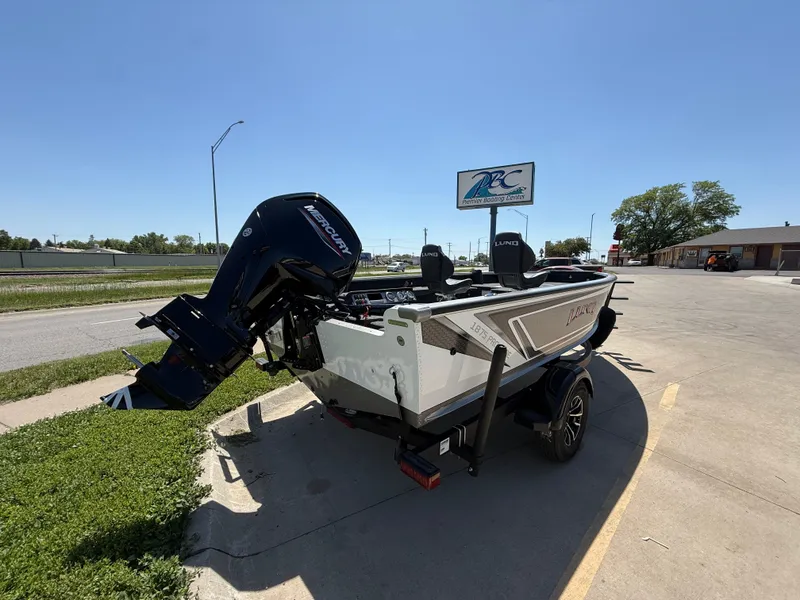 Slide: The Image of 2025 Lund 1875 Pro Guide boat with outboard motor parked on a sunny day. - 4