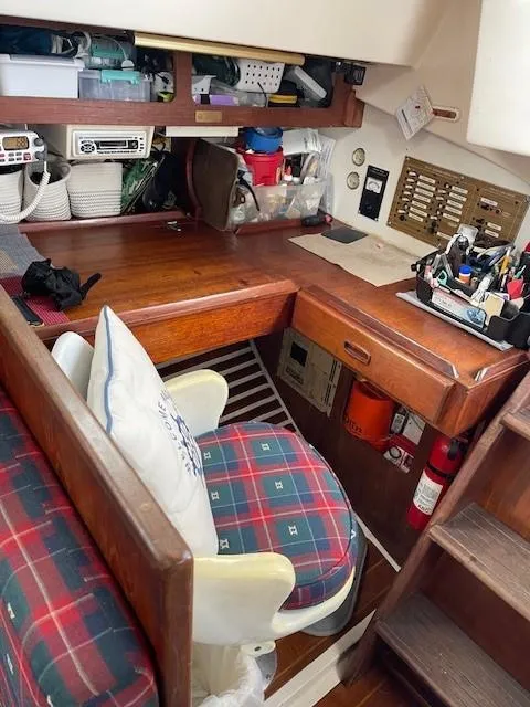 Slide: The Image of 1980 Hunter 36 sailboat interior with navigation desk and plaid cushioned seating. - 13