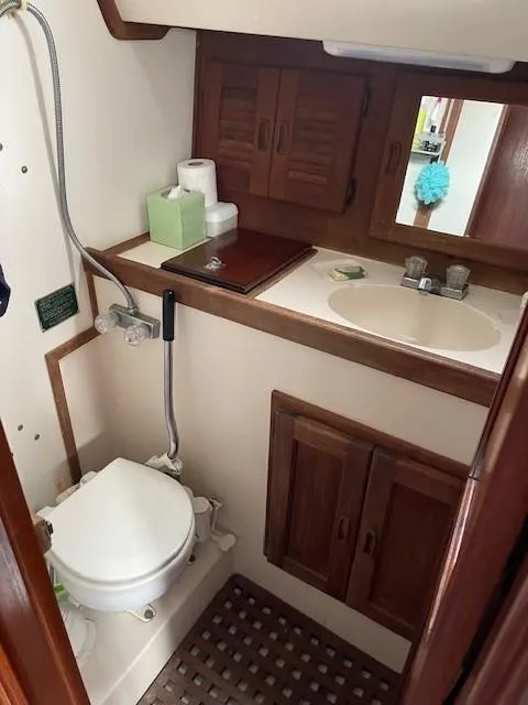 Slide: The Image of 1980 Hunter 36 yacht bathroom with wooden cabinets, sink, and marine toilet. - 18