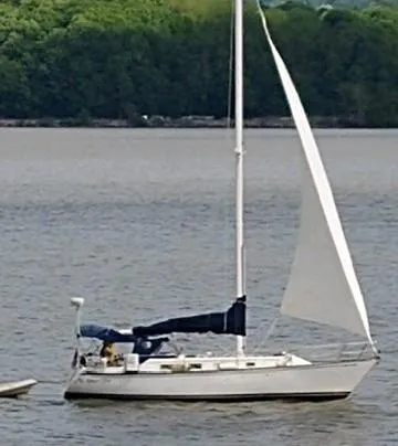 Slide: The Image of 1980 Hunter 36 sailboat on calm water with lush green forest background. - 2