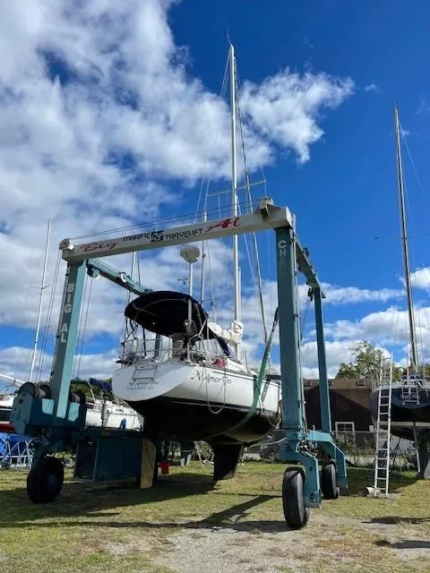 Slide: The Image of 1980 Hunter 36 sailboat on a lift under a blue sky with clouds. - 23