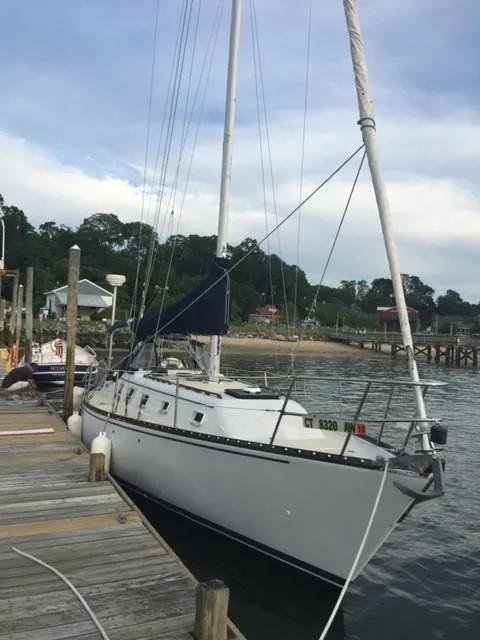 Slide: The Image of 1980 Hunter 36 sailboat docked by a wooden pier, calm waters, and lush greenery. - 4