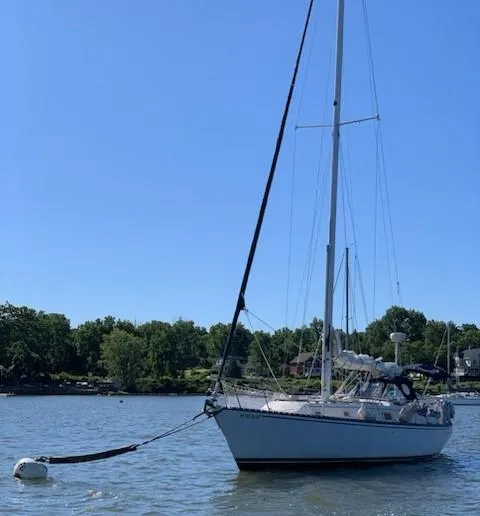 Slide: The Image of 1980 Hunter 36 sailboat anchored on calm water under clear blue sky. - 6