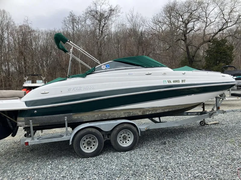 Slide: The Image of 2002 Four Winns 214 Funship boat on trailer, parked on gravel, with green canopy. - 1