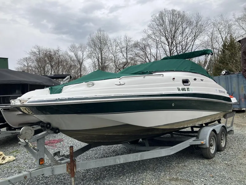Slide: The Image of 2002 Four Winns 214 Funship boat on trailer with green cover, parked outdoors. - 2