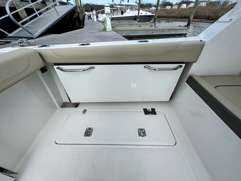 Slide: The Image of 2019 Pursuit DC 325 Dual Console interior with storage compartments, docked at marina. - 10